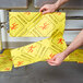 A person holding a yellow Spilfyter absorbent pad with a yellow warning sign.