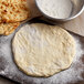 A wooden board with dough and Regal Atta flour.