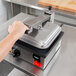 A hand using the Vollrath Cayenne Single Panini Sandwich Press to make a sandwich.