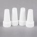 Three white plastic caps covering white cone-shaped piping tips.