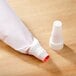A white Ateco piping tip cover with a pink tip on a table.