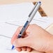 A person writing with a Uni-Ball Vision pen.
