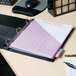 An Avery black heavy-duty view binder on a desk with pink and white pages inside.