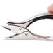 A hand holding a Swingline heavy-duty metal staple remover with a chrome finish.