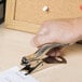 A hand using a Swingline heavy-duty metal staple remover to remove staples.