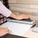 A person using a Swingline Precision Pro hole punch on a piece of paper.