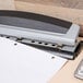 A Swingline Precision Pro hole punch on a table with a stapler and a calculator.