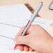 A person's hand writing with a Uni-Ball Vision roller ball pen.