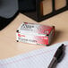 A box of Acco silver paper clips on a desk.