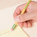 A hand using a Dixon Ticonderoga yellow pre-sharpened pencil to write on a note.