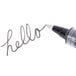 The gray and clear tip of a Uni-ball Vision roller ball pen writing in black ink.