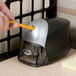 A person using a Bostitch QuietSharp Executive Electric Pencil Sharpener to sharpen a pencil.