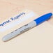 A blue Sharpie pen writing "house report" on paper.