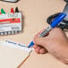 A hand using a Sharpie fine point marker to write on a piece of paper.