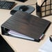 An Avery black heavy-duty view binder on a desk with papers inside.