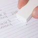 A person's hand holding a white Staedtler Mars plastic eraser.