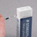 A person putting a Staedtler Mars white plastic eraser in a box.