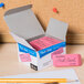 A box of Paper Mate Pink Pearl Erasers on a table with pencils.