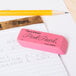 A Paper Mate Pink Pearl eraser on a piece of paper next to a pencil.