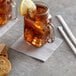 A glass mug with a silver and gray Choice beverage napkin with ice and a lemon slice on top of it.