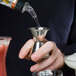 A person using an American Metalcraft stainless steel jigger to pour a cocktail.