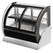 A Vollrath curved refrigerated countertop display case with glass doors.
