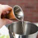 A person pouring liquid into an American Metalcraft copper Japanese style jigger.