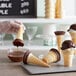 A person pouring Phillips Chocolate ice cream cone dip into an ice cream cone.