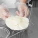 A person in gloves using a Tablecraft fry basket to hold a tortilla.