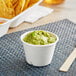 A cup of guacamole with chips on a table.