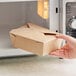 A hand holding a brown Choice Kraft paper take-out box.