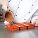 A chef pouring brown liquid into a Matfer Bourgeat mini cake mold.