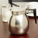 a silver coffee pot with a black handle