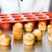 A Matfer Bourgeat orange silicone mini muffin mold filled with muffins.