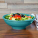 A Fiesta china pedestal serving bowl filled with salad and vegetables on a table.