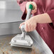 A person using the Garde Heavy-Duty Aluminum Grill Scraper to clean a metal container.