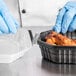 A person in blue gloves opening a Solo black plastic take-out container of food.