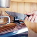 A person's hand using a Weston Pro Series Electric Meat Grinder on a counter.