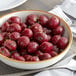 A bowl of Furmano's whole red beets on a table with a fork and knife.