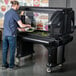 A man putting food into a Cambro portable salad bar on a table.