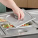 A hand holding a Vigor stainless steel tray with food in it.