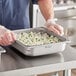 A person using a Vigor stainless steel steam table pan to serve rice and peas.