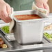 A person holding a Vigor stainless steel tray of food with a cloth