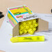 A yellow highlighter from a box on a desk next to a yellow sticky note.