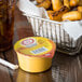 A container of Muy Fresco Cheddar Cheese Sauce on a table with food and a drink.