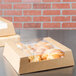 A Kraft bakery box of pastries on a table.