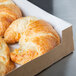 A Kraft bakery box with a window filled with croissants.