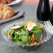 A vegetable salad in a Fineline clear plastic bowl with a fork and knife.