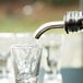 An Acopa stainless steel liquor speed pourer pouring water into a glass.