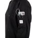 A person wearing a black Mercer Culinary chef jacket with a pocket full of tools on a professional kitchen counter.